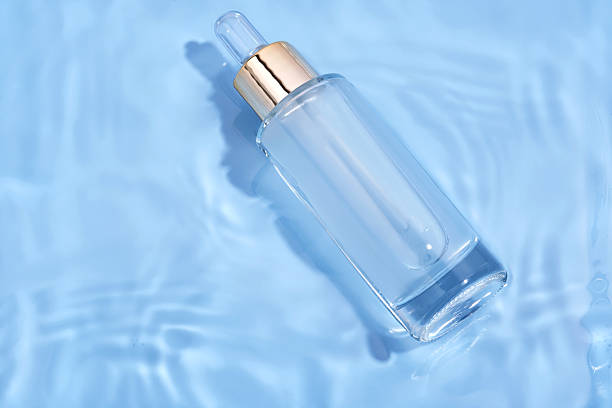 istock Bottle with moisturizing serum in water on blue background. 2244577966