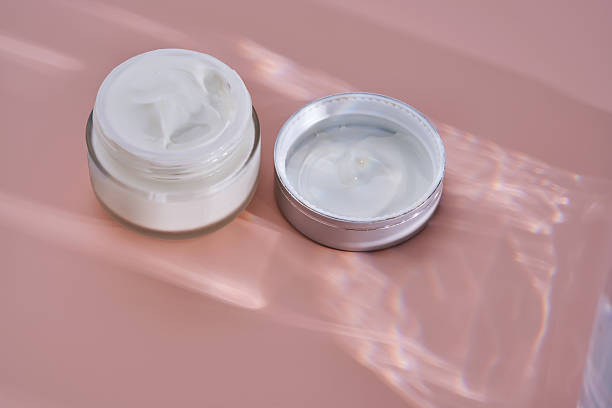 istock An open jar of cream with its texture on a pink background. 2244578238