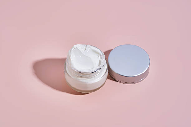 istock An open jar of cream with its texture on a pink background. 2244579659