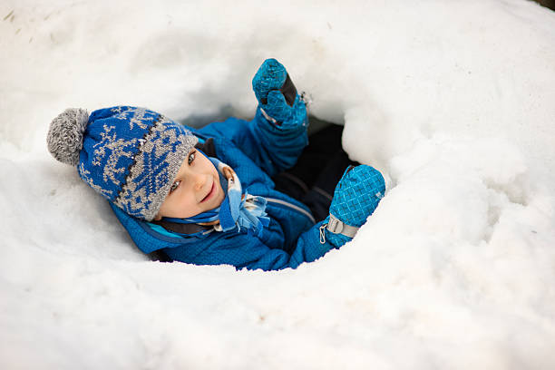 istock Young boy playing in deep snow hole looking up at camera with happy smile 2244579925
