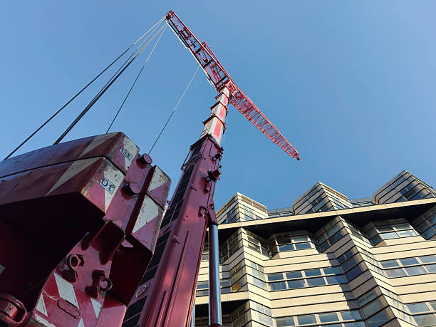 istock Low-angle view of a red construction crane next to a modern building 2244580409
