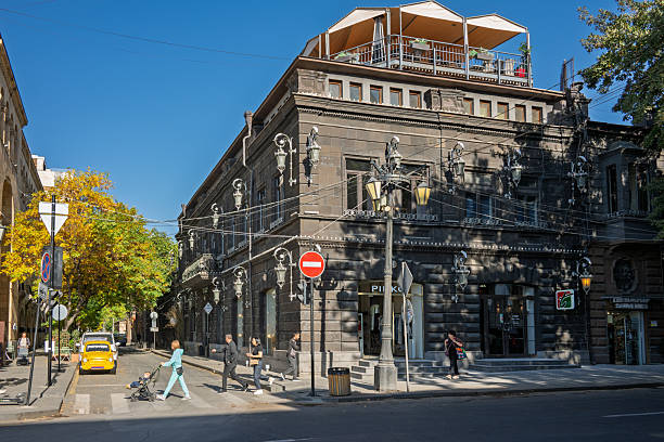 Yerevan, Armenia 10.16.2025. A busy street with a red sign on the corner. People are walking and standing on the sidewalk