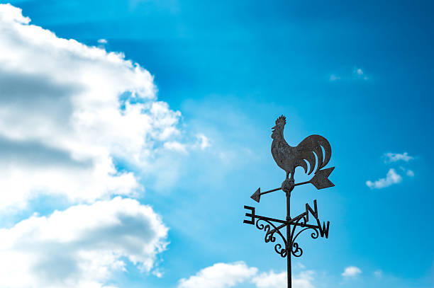 Typical, wrought iron weather cock pointing to a southerly wind in the remote British isles. A storm front is set to bring heavy rain and gales.