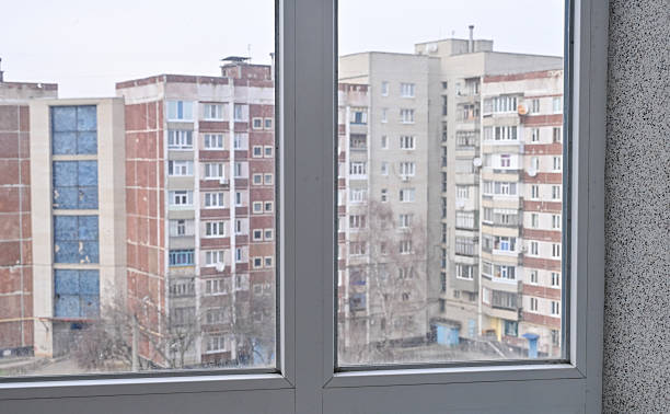 istock Frosted glass window with plastic frame inside apartment. Blurred city view outside. 2244584907