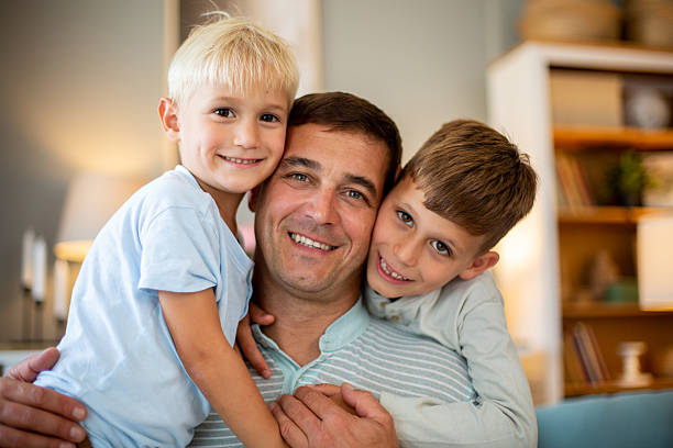 istock Father and two sons hugging, smiling and bonding indoors 2244589041