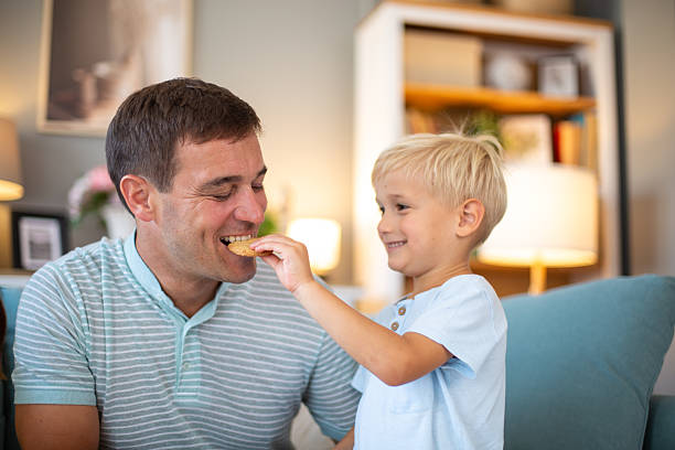 istock Son sharing cookie with happy father at home 2244589821