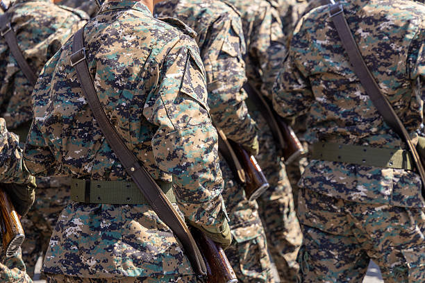 istock Multiple men in camouflage uniforms carrying rifles outdoors at sunny day 2244590075