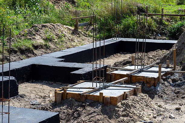 istock Wide foundation strips painted with black dispersion asphalt-rubber mass, visible reinforced concrete column rods. 2244600965