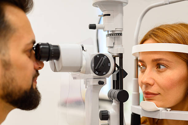 istock Male ophthalmologist examining young female patient's eyes using slit lamp during vision checkup at clinic 2244601366