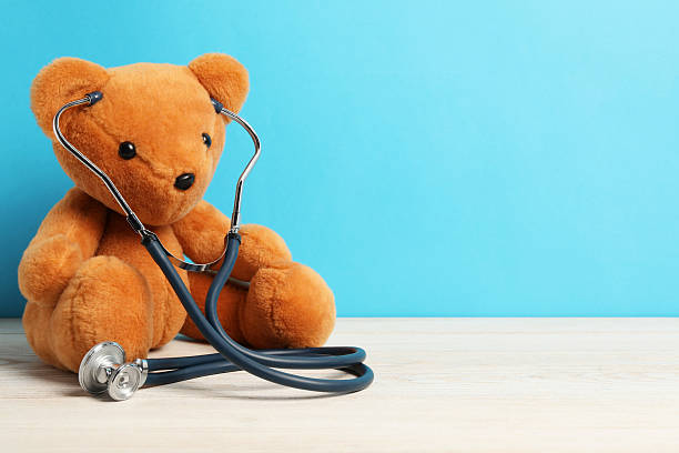 istock Pediatrics concept. Teddy bear with stethoscope on wooden table against light blue background, space for text 2244604951