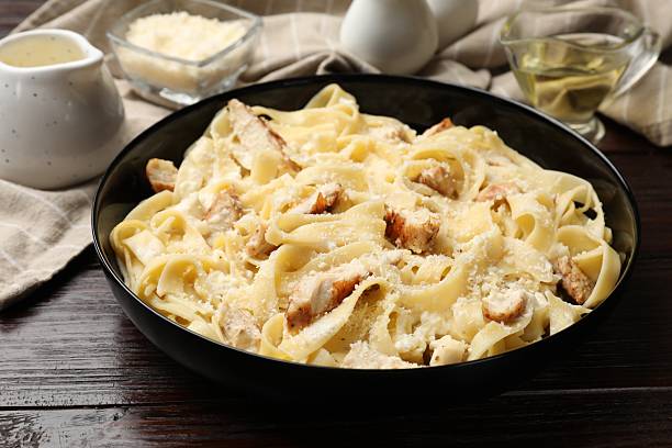 istock Tasty Alfredo pasta with chicken on wooden table 2244606302
