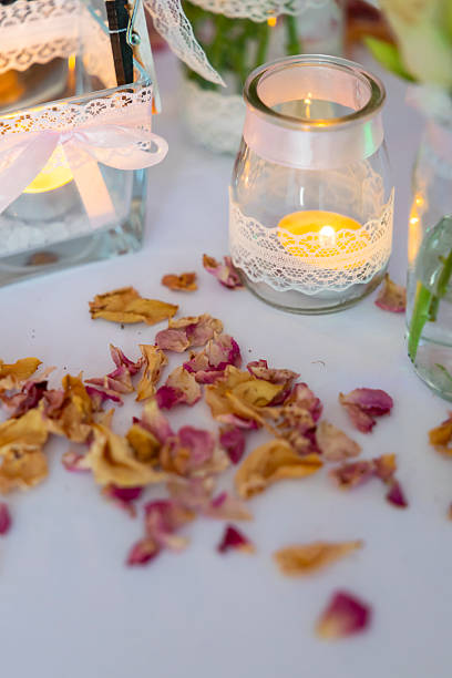 Tealight candles in decorated glass jars with lace and ribbon, surrounded by rose petals
