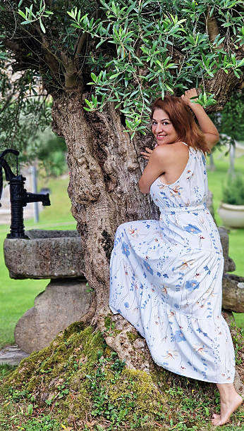 istock Woman smiling leaning against an old olive tree 2244608696