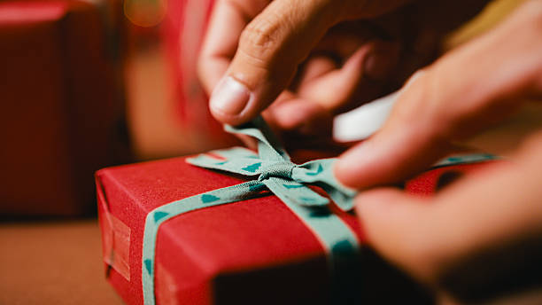 istock Hands Tying Ribbon On Christmas Gift Box 2244618386