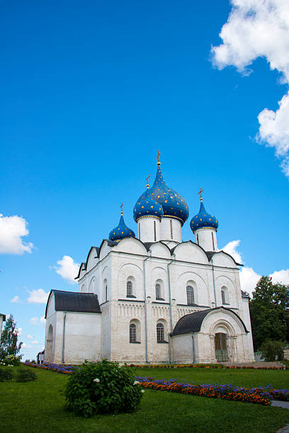 The majestic Nativity Cathedral with its iconic blue, star-dotted domes, standing in the historic Suzdal Kremlin under a bright blue sky.