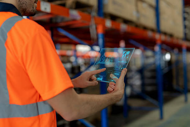 istock A warehouse employee analyzes data on a futuristic glass screen with interactive infographics to control robots for product picking. Modern logistics, warehouse automation, AI, and efficiency in supply chain management and technology-driven business. 2244621165