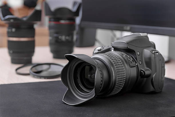 istock Digital camera with lens aand petal-shaped sunshade on a dark surface. 2244626918