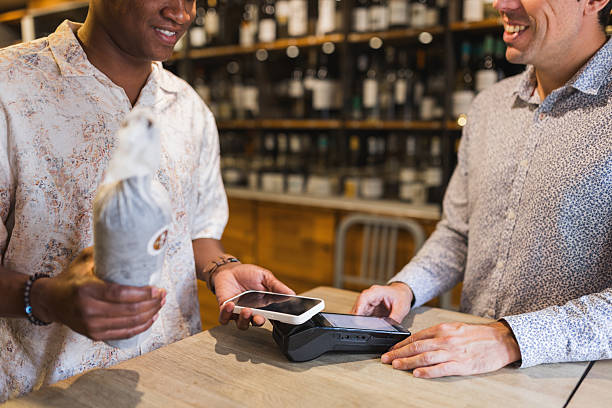 istock Man paying for wine with smartphone in retail store. 2244632075