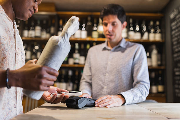 istock Man paying for wine with smartphone in retail store. 2244632078