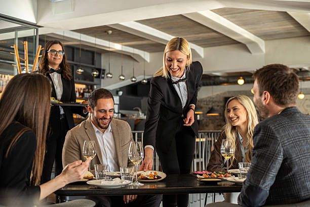 istock Waitress serving meal to happy friends dining in restaurant 2244632155