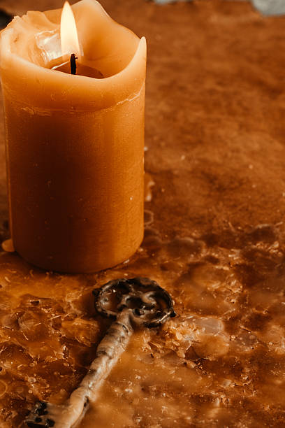Burning candle and an old key on an aged background