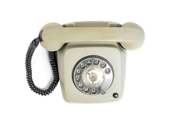 old-fashioned rotary dial telephone with a gray body, placed on a wooden surface. The phone shows signs of wear and age, evoking retro or communist-era design.