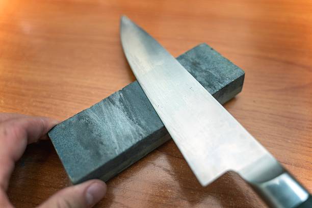 istock Sharpening a large kitchen knife on a special whetstone, demonstrating proper tool maintenance for culinary content 2244637352