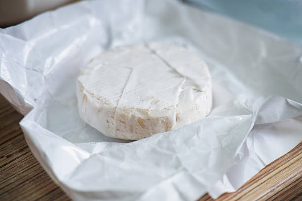 A freshly unwrapped round Camembert cheese with white mold, ready for gourmet dining and food photography.