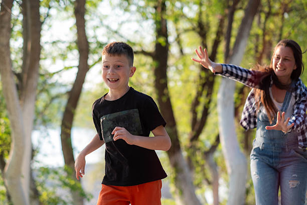 Happy boy running from a woman chasing him in a park