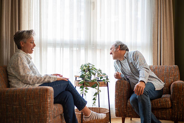 istock Mature woman talking to her husband while relaxing together on a sofa at home 2244639557