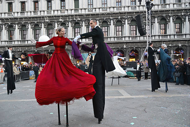Venice, Veneto, Italy - February 12th, 2013: Two mask participants of the 2013 Carnival celebrations posing for casual photographers and tourists in St. Mark's square. Campanile seen in the background.