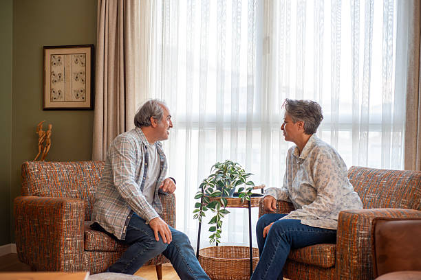 istock Mature woman talking to her husband while relaxing together on a sofa at home 2244640249