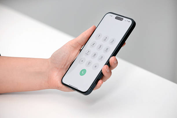 istock Woman holding smartphone with dialer application at white table against blurred background, closeup 2244641545