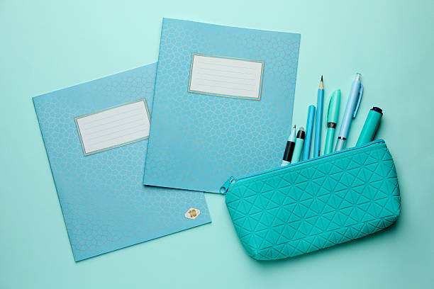 Copybooks and other school stationery on light blue background, flat lay