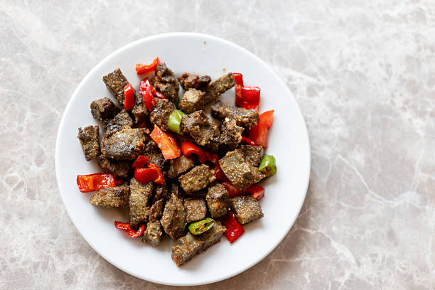 Turkish traditional fried liver dish with bell peppers, arnavut cigeri, on a marble table