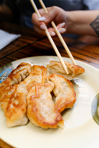 istock Woman eating crispy pan-fried dumplings with chopsticks 2244643967