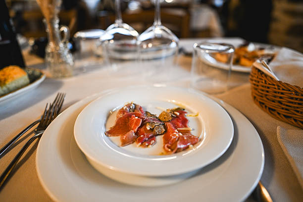 Delicious beef carpaccio with black truffle and pine nuts served on a white plate