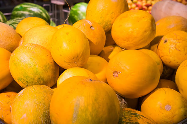 Melons lie in a pile on the counter of a vegetable store