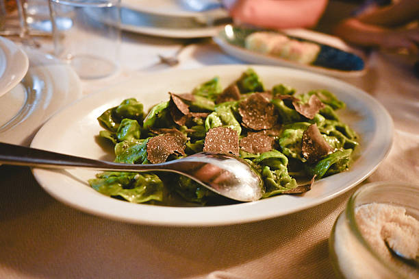 Plating italian tortellini topped with gourmet black truffle at a restaurant