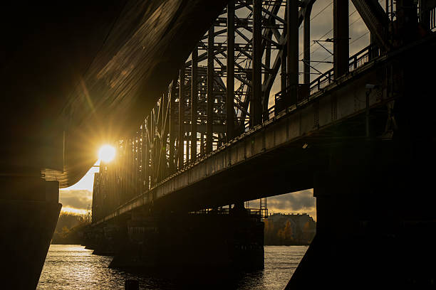 istock Underbridge view of Riga railway bridge at sunset showing structural design, steel framework, and light reflections on water illustrating industrial engineering and architectural composition of Latvia 2244658164