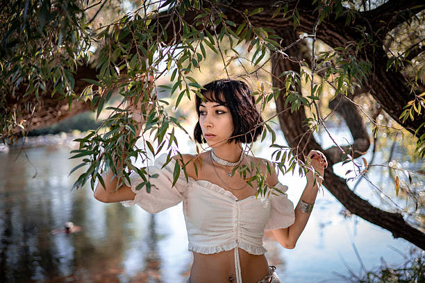 Art beautiful romantic woman lies in swamp in blue long dress with flowers. Portrait brunette in transparent dress in water swamp mud duckweed. Book cover