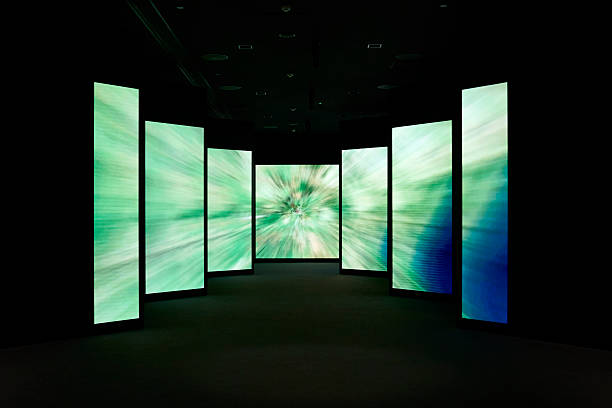 A modern art installation featuring illuminated panels with dynamic green patterns in a dark room.