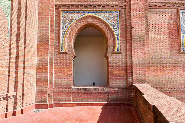 A detailed view of a brick wall with an ornate archway and colorful tiles in a historical building.