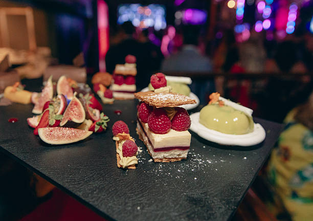 Elegant Dessert Platter With Raspberry Cake, Fig Slices, And Green Mousse At A Night Party