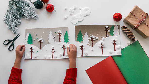 istock Child's hands crafting a winter scene with paper, cotton, and decorations 2244662014