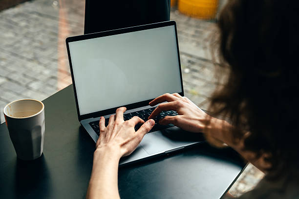 istock Person working on laptop at a cafe table with coffee cup during morning hours 2244666194