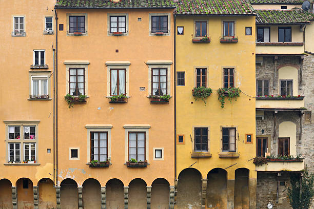 Close-up view of a riverside building in Florence, Tuscany, Italy. The scene shows walls with arched supports and window flower boxes characteristic of the city’s Renaissance-era architecture.