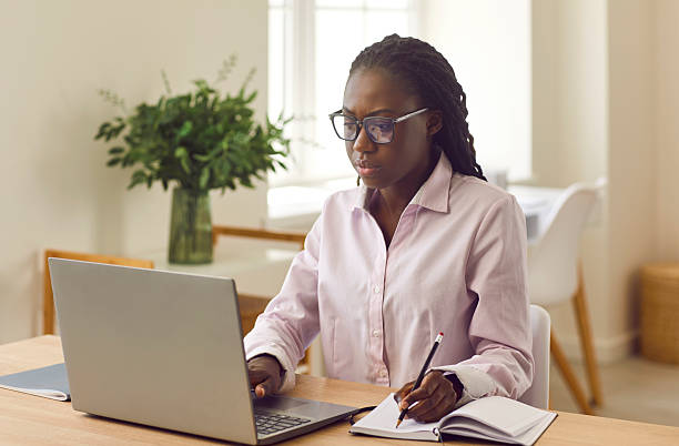 istock Young African American woman studying online, using laptop and taking notes in notebook 2244667205