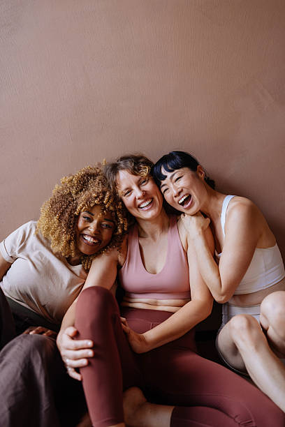 istock Three Friends Laughing Together During Casual Workout Session, Sitting Against Pink Wall 2244668524