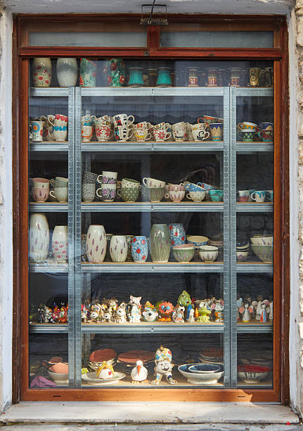 istock Colorful ceramic pottery displayed in a shop window, showcasing various mugs, vases, and decorative items arranged on shelves, highlighting craftsmanship and artistic design in a vibrant setting 2244669466